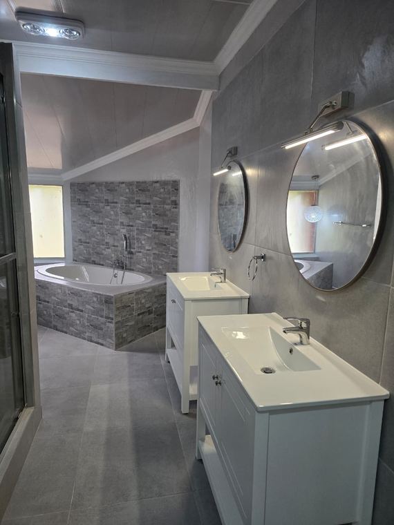 Twin vanities with round mirrors and a fitted bath