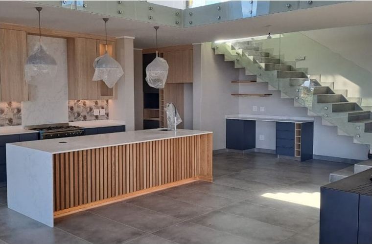 Kitchen island and fitted cupboards beside a staircase